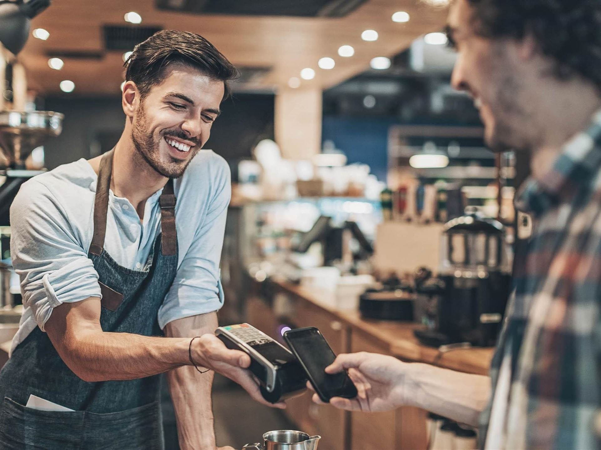 Mann bezahlt im Café mit seinem Smartphone