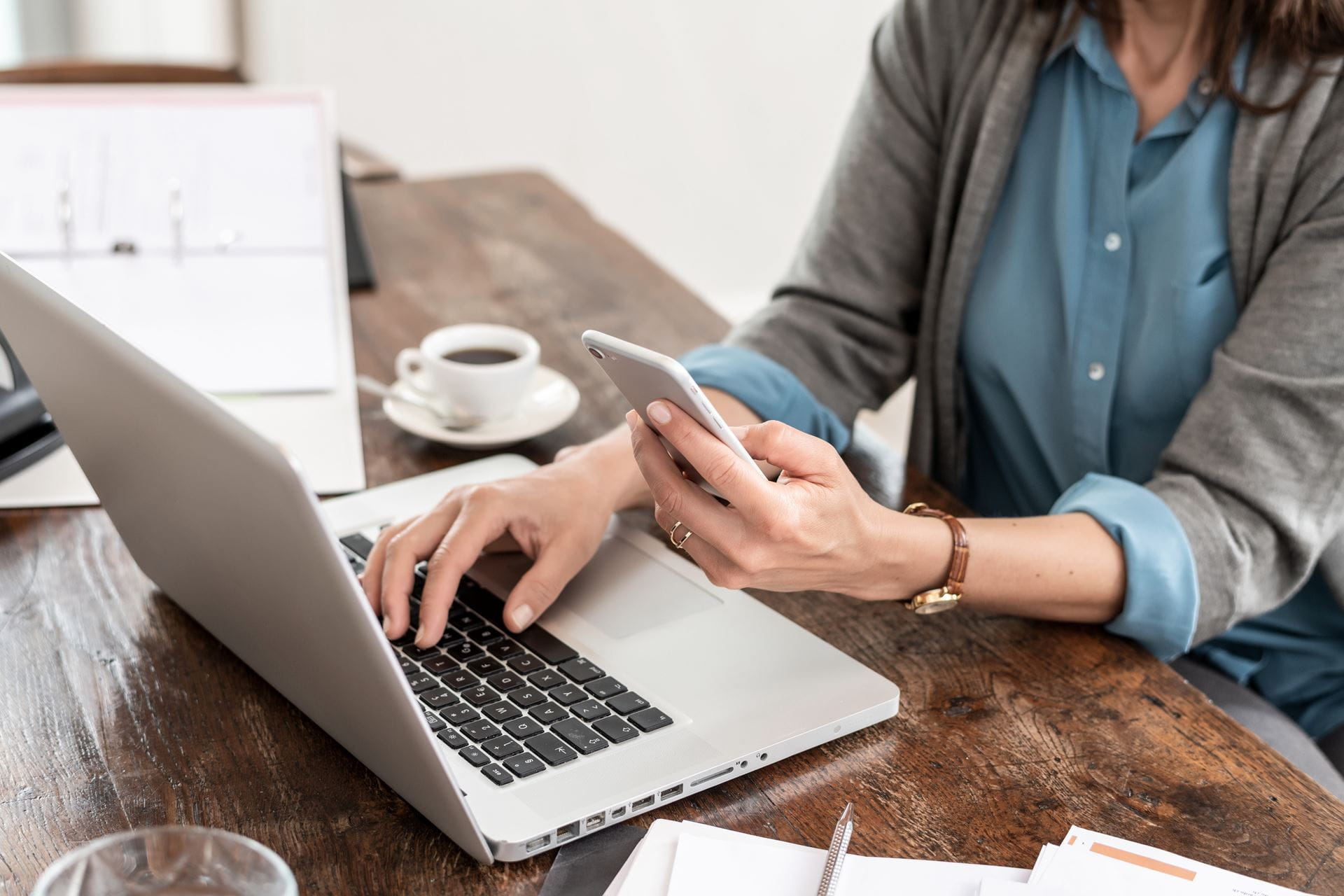 Frau mit Laptop Smartphone und Kaffe an Holztisch