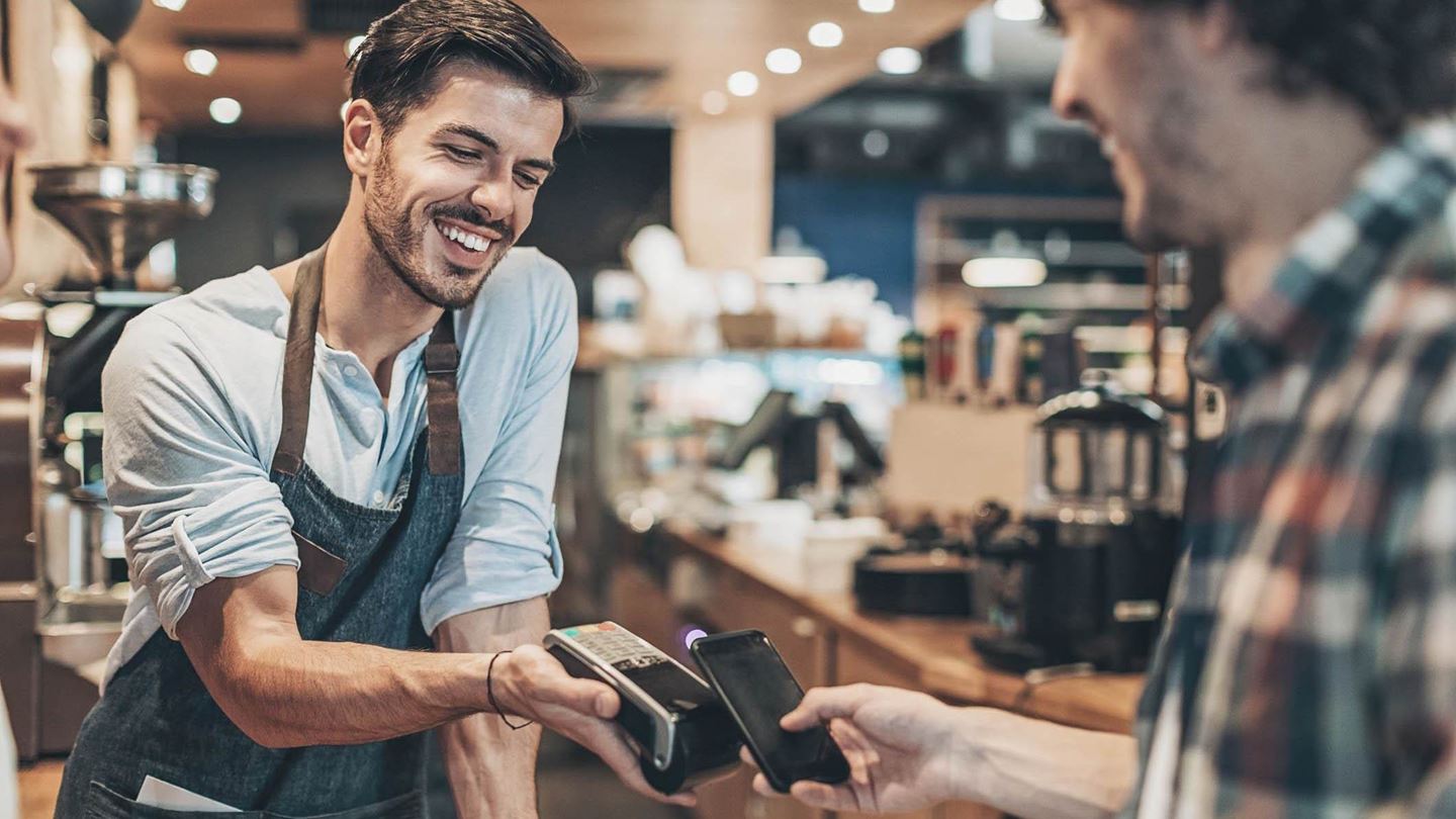 Mann bezahlt im Café mit seinem Smartphone