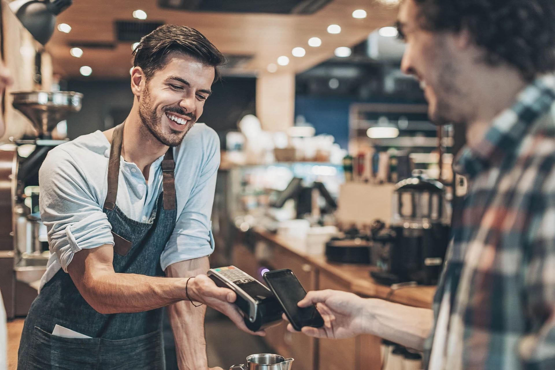 Mann bezahlt im Café mit seinem Smartphone