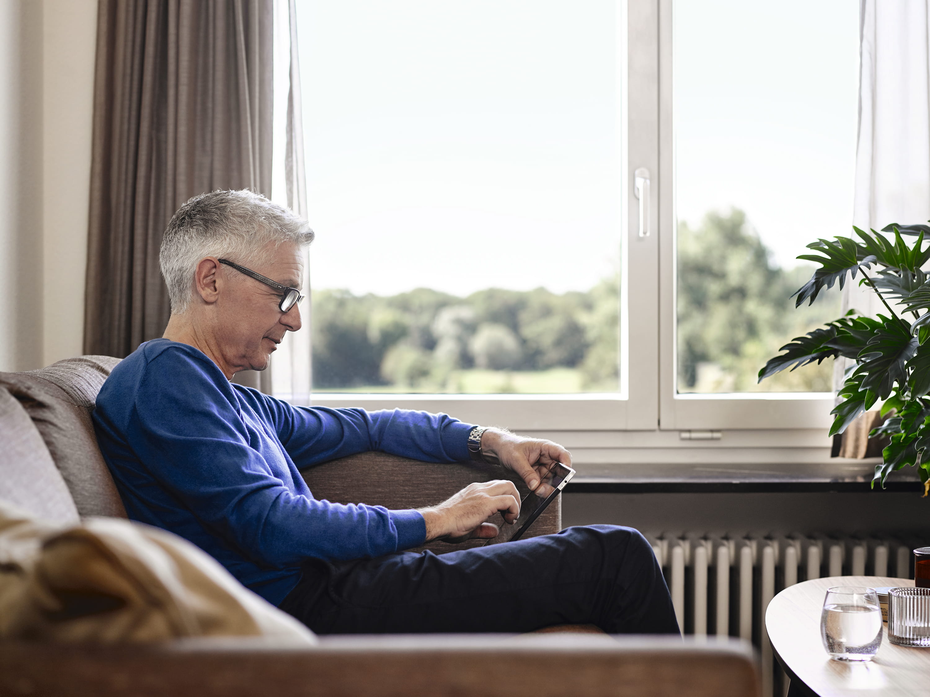 Senior an Tablet im Wohnzimmer