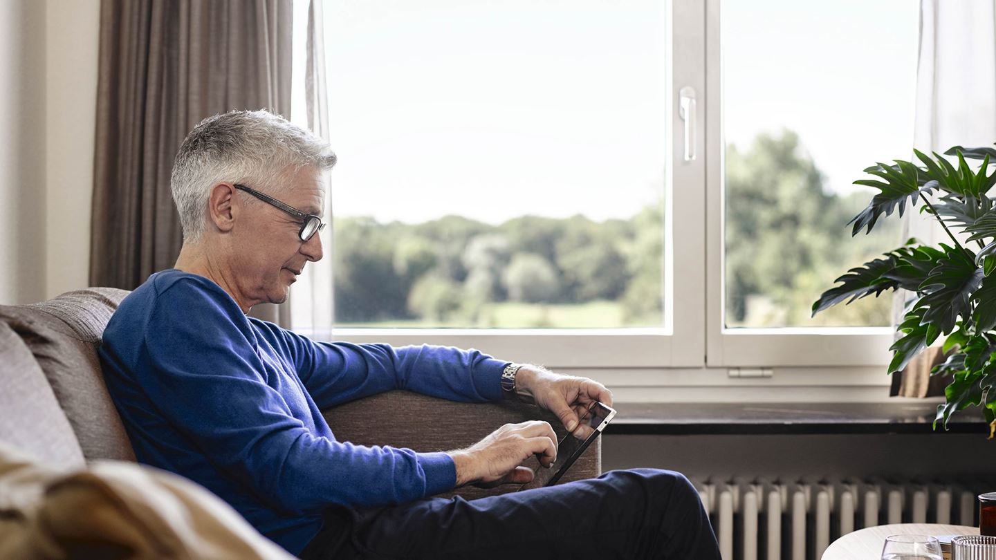 Senior an Tablet im Wohnzimmer