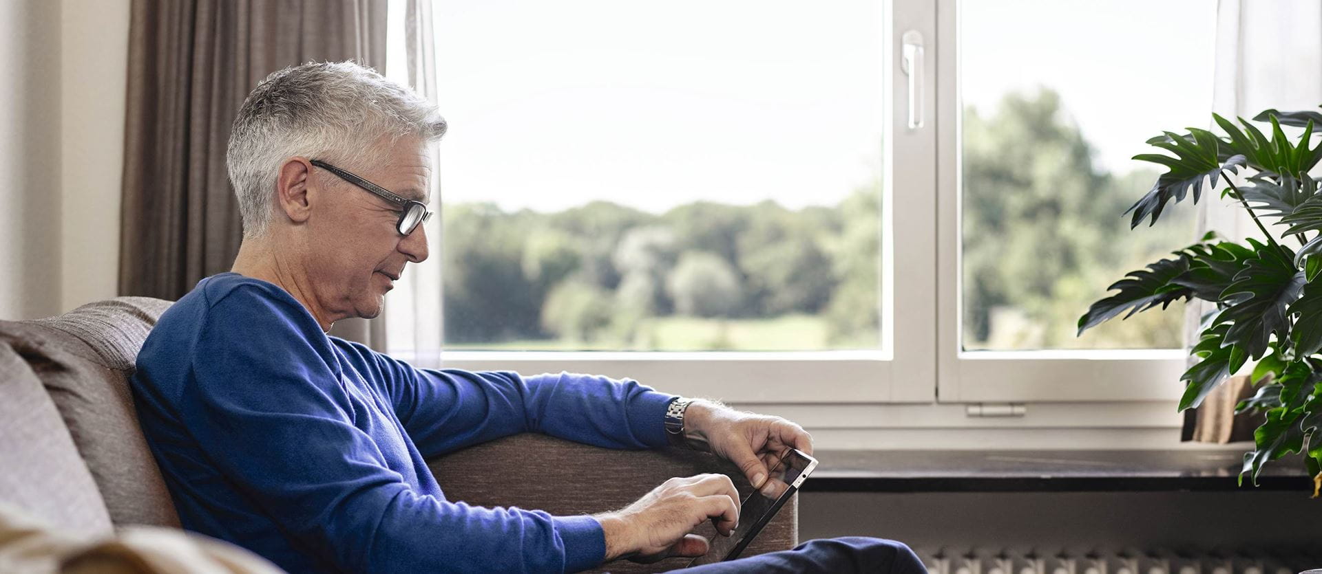 Senior an Tablet im Wohnzimmer